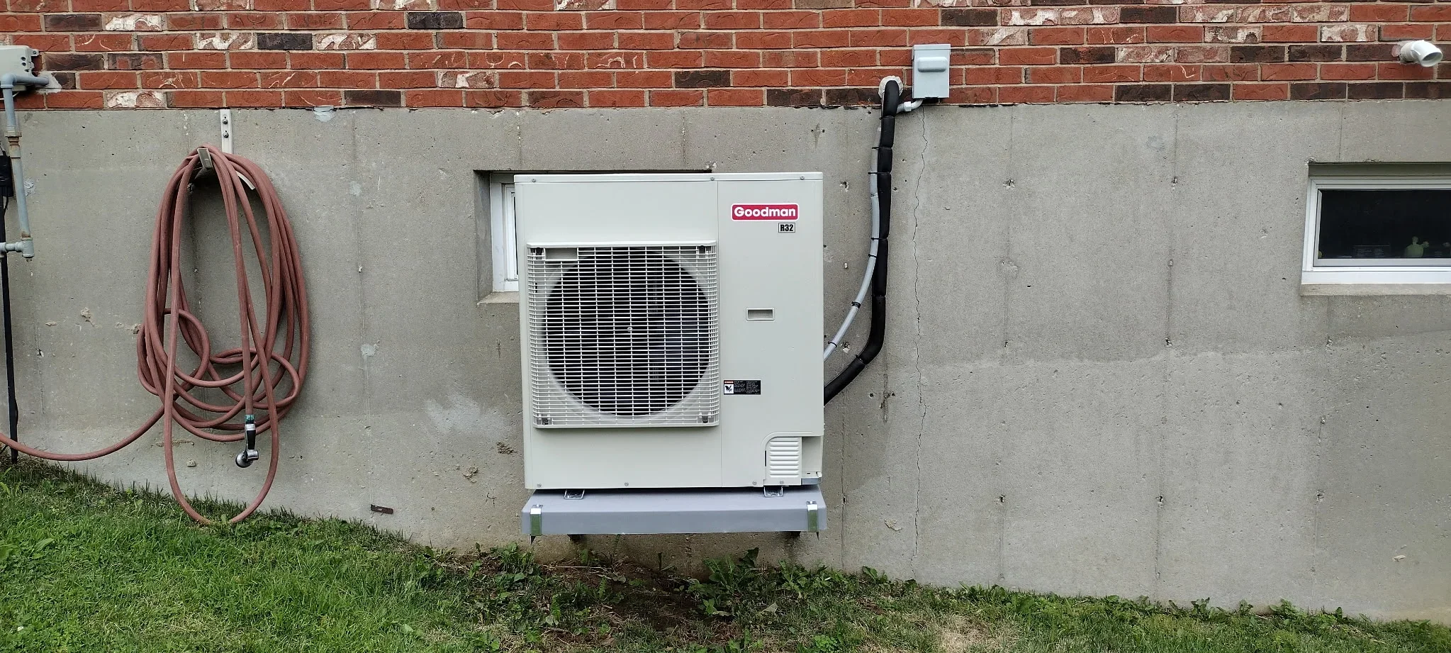Goodman B2 heat pump unit installed on concrete foundation with refrigerant lines and electrical connections